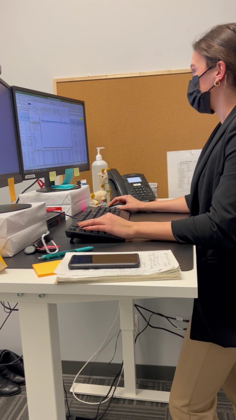 Woman looking at open tabs on a desktop at her standing desk