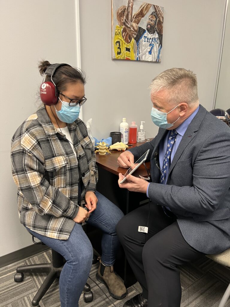 Healthcare professional assisting a patient with an auditory test