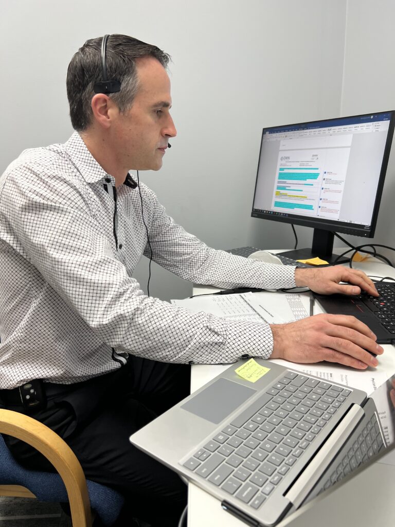 Man wearing wired headset working at his desk on his laptop