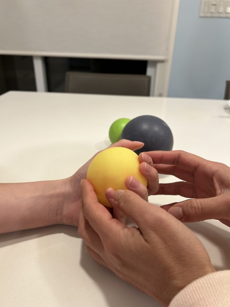Therapist helping a person properly use a hand therapy ball