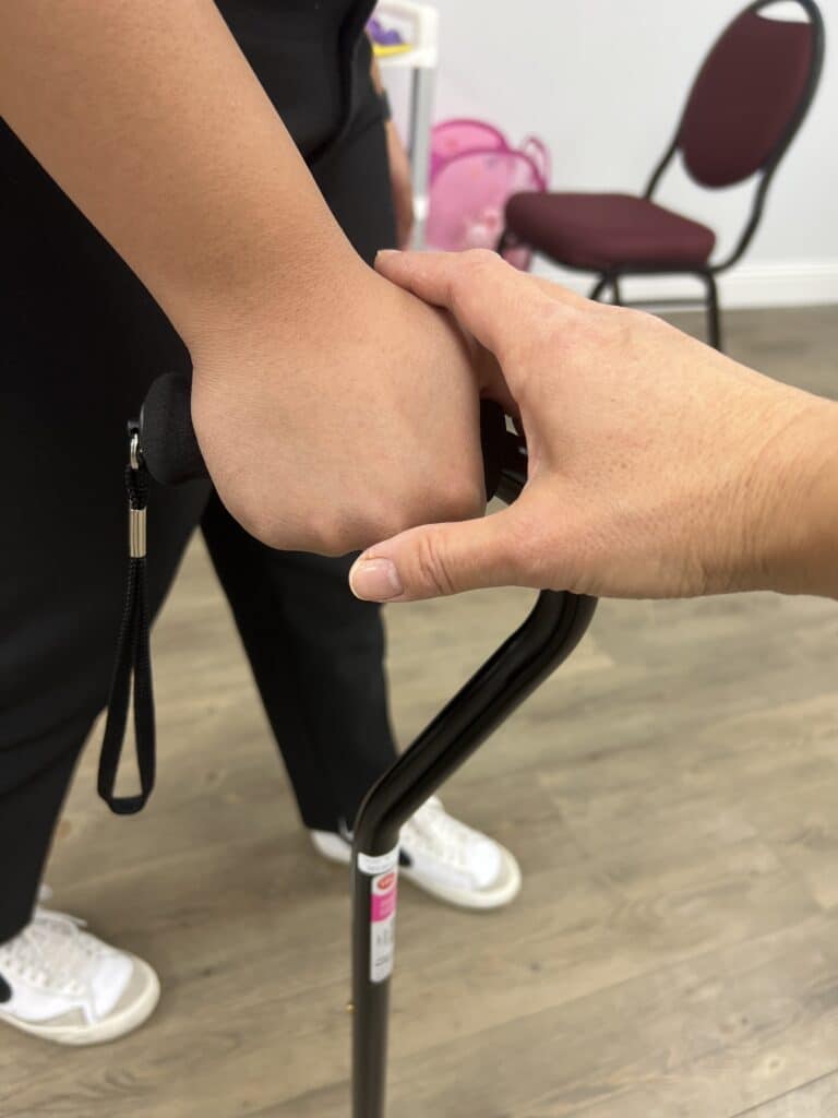 Therapist helping a person walk with their cane